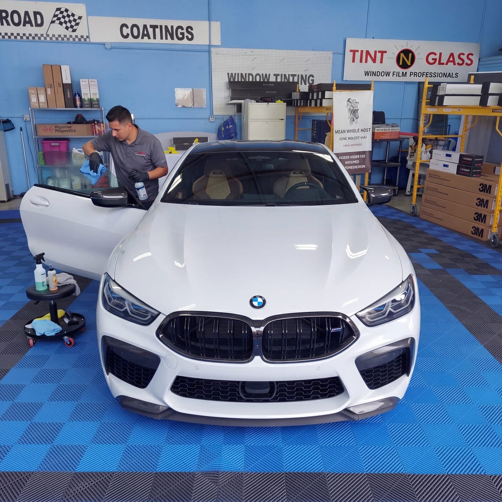 White BMW being prepared for ceramic window tinting inside the Tint N Glass bay