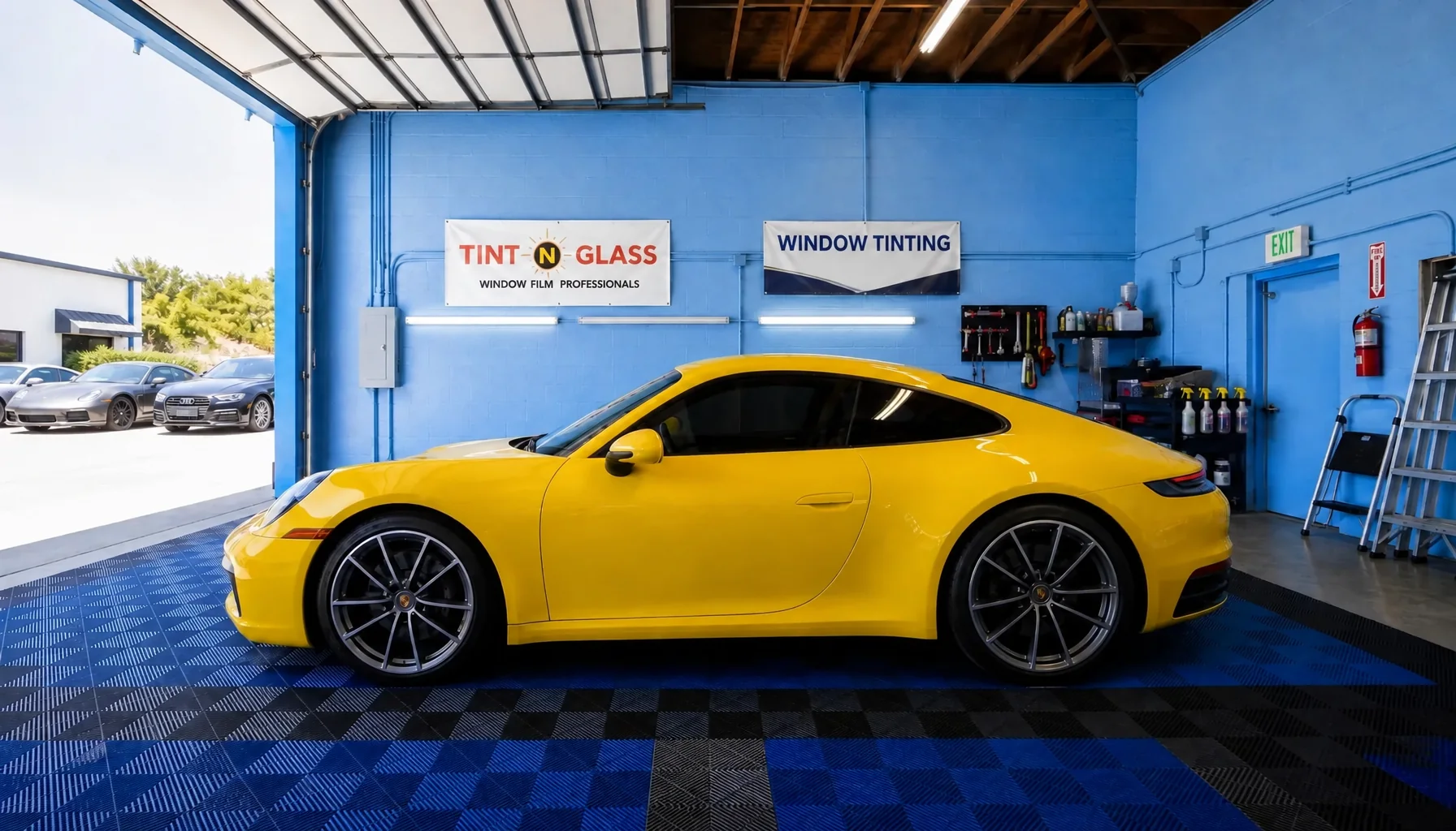 A yellow Porsche 911 with tinted windows in a tint bay
